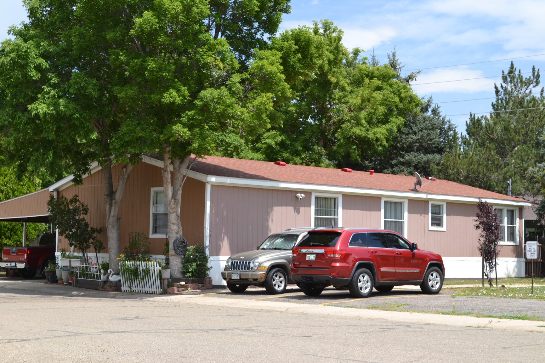 Room to park, room to breathe — A double-wide with covered carport tucked beside mature ash trees.